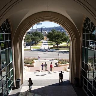 TCU学生走过以足球场为背景的大学联盟拱门